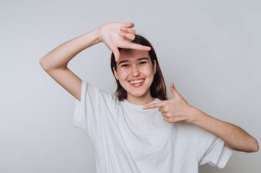 Asyalı genç bir kadın, elleri arka planda hareket ederken gülümseyerek sıradan bir portre için poz veriyor.