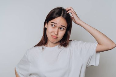 Tarafsız bir arkaplanda genç bir kadının kafasına sıradan bir kıyafetle dokunmasının yarattığı şaşkınlık.