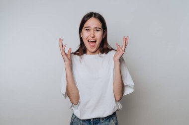 Heyecanlı genç bir kadın, sıradan bir ortamda sade bir geçmişe karşı neşe ve coşku ifade ediyor.