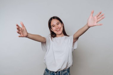 Genç Asyalı kadın gülümsüyor ve kollarını açık bir şekilde arka planda rahat bir şekilde uzanıyor.