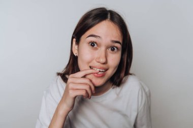 Genç Asyalı kadın gülümsüyor ve ev ortamında parmaklarını hafifçe ısırıyor.