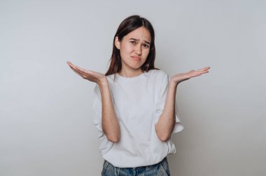 Şaşkın bir ifadeye sahip genç bir kadın gün boyunca elleri tarafsız bir ortamda hareket eder.