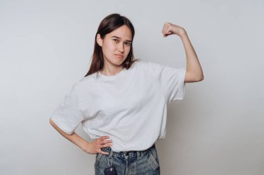 Güçlü, genç bir kadın, kaslarını açık havada gösterirken kendine güvenerek poz verir.