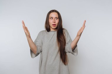 Şaşırdığını ve şaşırdığını ifade eden genç bir kadın kollarını hafif bir arka plana uzatmış.