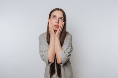 Karışıklık ve endişeyi ifade eden bir kadın. Minimalist bir ortamda elleri yüzündeydi.