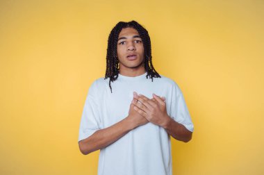 Kıvırcık saçlı genç adam, parlak sarı bir arka plana şaşırdığını ifade ediyor.