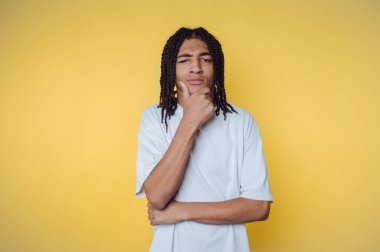 Kıvırcık saçlı genç, parlak sarı bir arka planı olduğunu düşünüyor.