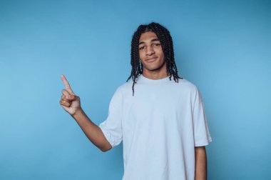 Gençlik jestleri, kapalı bir alanda, sıradan bir kıyafetin içinde saf mavi bir arka plana karşı dururken olumlu yönde olur.