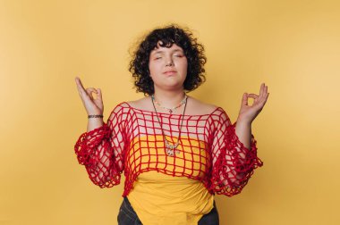 Parlak sarı bir arka planda huzur içinde meditasyon yapan bir insan.