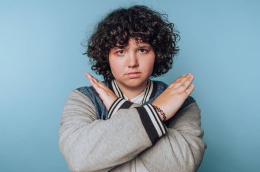 Delikanlı, mavi bir arkaplan karşısında küstah bir tavır sergiliyor.