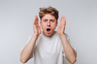 Genç adam, ağzı açık ve elleri tarafsız bir arkaplanda kaldırılarak şoka girdi.