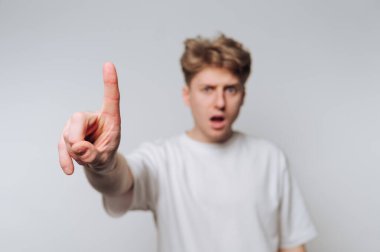 Sarı saçlı, bir parmağı arka planda olan, şaşırmış ya da şok olmuş görünen biri. Parmağına odaklan..