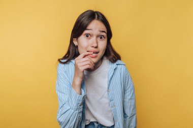Genç bir kadın şakacı bir şekilde dudağını ısırıyor. Utangaçlık ve merak belirtileri gösteriyor.