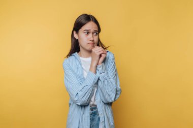 Düşüncelere dalmış genç bir kadın, parlak sarı bir arka plana karşı tavrı ve düşünceleri yansıtıyor..