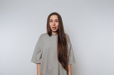 Şaşırmış bir kadın, şaşkınlığını geniş gözleri ve açık bir ağızla gösterir. Duygusal tepkisini beyaz arka planda vurgular.