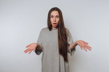 Şaşırmış bir kadın elleri havada, beyaz arka planda duygusal tepkiler gösteriyor.