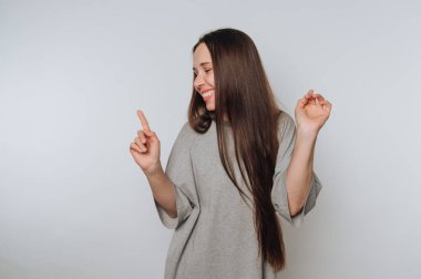 Neşeli kadın parmak havada dans eder, beyaz arka planda mutluluk ve neşe saçar.