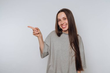 Gülümseyen kadın sevinçle işaret eder, beyaz arka planda mutluluk ve başarı duygusu taşır.