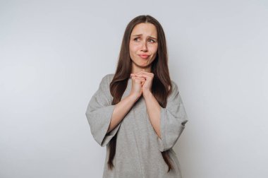 Yüzünde yalvaran bir ifadeyle genç bir kadın beyaz arka planda umutlarını ve arzularını kurnazca aktarıyor.