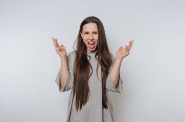 Genç kadın ellerini havaya kaldırıyor, beyaz arka planda zafer dolu bir anın tadını çıkarıyor.