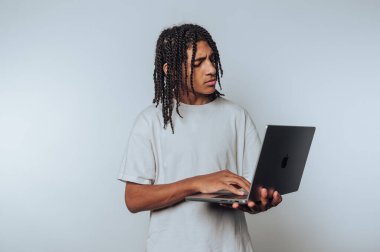 Genç adam özenle dizüstü bilgisayara yazar, özveri ve yaratıcılığı bembeyaz arka planda somutlaştırır