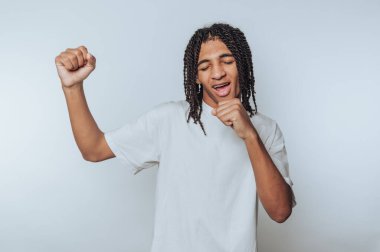 Genç adam neşeli bir şekilde şarkı söylüyor, beyaz arka planda mutluluğu ve tasasız ruhu somutlaştırıyor.