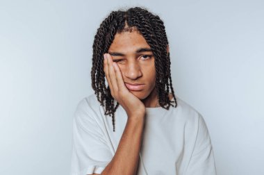 Genç adam yorgun görünüyor, beyaz arka planda tefekkür etmek için başını elinin üzerinde dinlendiriyor.