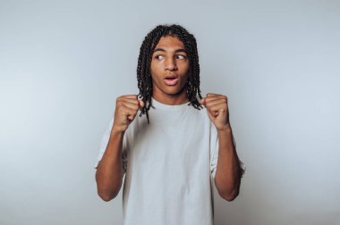 Genç adam şaşkınlık dolu bir bakışla dövüşüyor, beyaz arka planda tepkiyi ve hazırlığı vurguluyor.