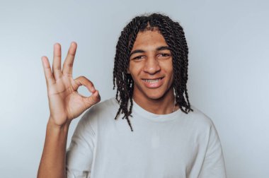 Genç adam beyaz arka planda kendine güven ve pozitiflik gösteren bir gülümseme ile 