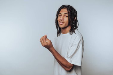 Neşeli genç insan gülümserken ellerini kaldırır, beyaz arka planda kaygısız bir ruhu somutlaştırır.