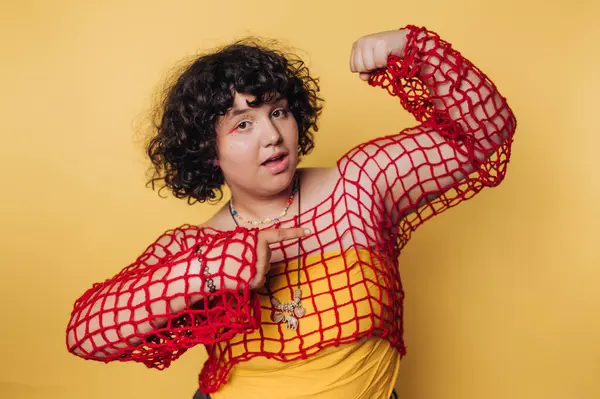 Genç bir kadın sarı arka planda renkli bir elbise giyerken neşe ve güven saçıyor.