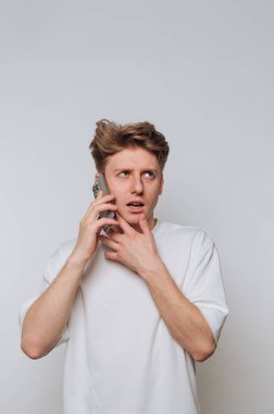 Genç adam telefonda arka planda konuşurken şaşkınlığını dile getiriyor.