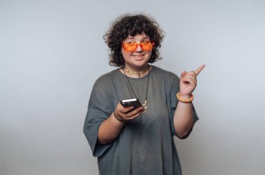 Renkli gözlükler takan kişi telefonu tutar ve keyfi bir şekilde el kol hareketi yapar.