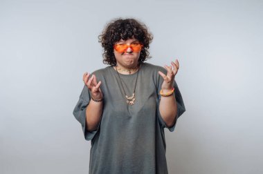 Tarafsız bir stüdyo ortamında güneş gözlüğü takarken hayal kırıklığını ifade eden kişi