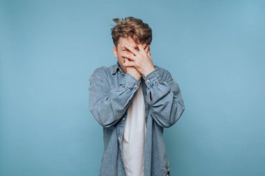 Delikanlı, duygusal bunalım anında yüzünü masmavi bir arka plana kapatarak hayal kırıklığını ifade ediyor.