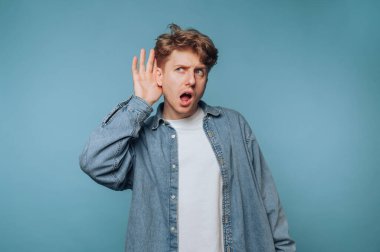 Genç adam, sıradan bir iç mekan ortamında mavi arka planda dikkatle dinlerken şaşırdı.