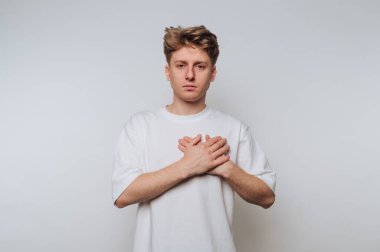 Tarafsız ifadeye sahip genç bir adam, sade arka planda el ele tutuşup, duygularını ve iç gözlemlerini aktarıyor.