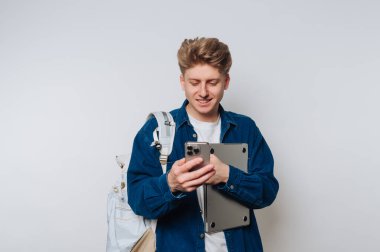 Öğrenci akıllı telefonu kontrol ederken ve bilgisayarını modern kapalı ortamlarda tutarken gülümsüyor