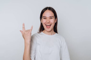 Genç bir kadın, arka planda neşeli bir ifadeyle el hareketi yapıyor.