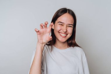 Gülümseyen genç kadın arka planda bir pençe hareketi yapıyor.