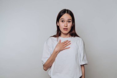 Gün ışığında stüdyo ortamında elleri göğsünde sürpriz yapan bir kadın.