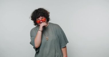 Genç kıvırcık kadın parlak bir gülümseme sergiliyor, neşe ve pozitiflik yayıyor, beyaz arka planda çekici ve canlı bir görünüm sergiliyor.