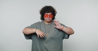 Genç bir kadın tesadüfen kenarda yürüyor, rahat bir tavır ve şık bir görünüm sergiliyor, beyaz arka plandaki moda eğilimlerini vurguluyor.