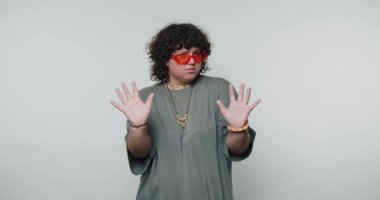 Neon güneş gözlüklü kadının şaşırmış ifadesi beyaz arka planda bir şaşkınlık anını yakalar.