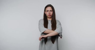 Tatminsiz bir kadın başını sağa sola sallıyor ve ellerini beyaz bir arka plana koyuyor. Etkileyici kadın kapalı mekan ortamında sözsüz bir tepki gösteriyor.