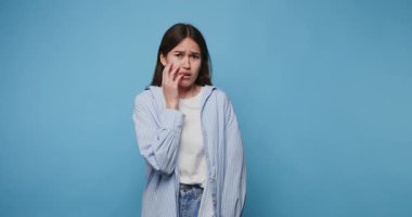 Genç kadın, kapalı alanlarda yakalanan duygusal anlar sırasında basit mavi arkaplandan duyduğu endişeyi dile getiriyor