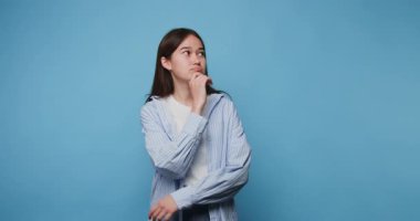 Genç bayan, mavi bir arkaplanda seçenekleri düşünceli bir şekilde değerlendiriyor.