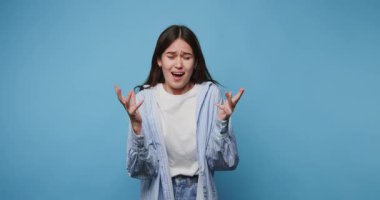 Kadın, yaratıcı bir performans sırasında mavi bir arkaplan önünde karmaşık duygular ifade eder.