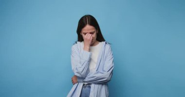 Duygusal bir anda mavi arka planda üzüntüsünü ifade eden bir kadın.