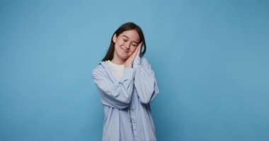 Neşeli genç bir kadın, parlak bir stüdyoda mavi çizgili bir gömlek giyerek huzurlu bir anın tadını çıkarıyor.